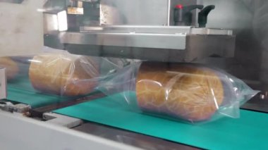 Fabrika taşıma bandında paketlenmiş sosisler, fabrikanın yiyecek paketleme bölümünde bir taşıyıcı bantta mühürlü sosisler.