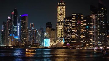 BAE, Dubai - Birleşik Arap Emirlikleri 01 Nisan 2024 Şehir Işıkları: Nighttime Skyline by the Water, Night view of a city skyline skyline with skylines with skyscrapers lit against the night sky,