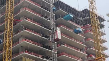 Turna kulesi olan kentsel inşaat alanı, inşaat halindeki çok katlı binanın çok katlı görüntüsü, vinç ve güvenlik bariyerleri var.