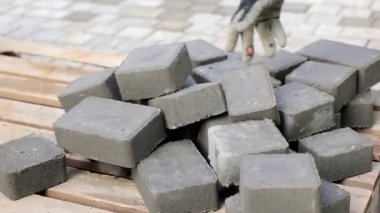 Beton Pavers 'ın yakın çekimi, ahşap bir paletin üzerine yığılmış gri beton kaldırımların yakın görüntüsü, dokuyu ve sağlam inşaat malzemelerini vurguluyor.