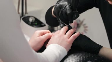 Müşteri çivileri üzerinde çalışan tırnak teknisyenlerine yakın çekim. Eldivenli bir tırnak teknisyeni bir kuaförde müşteriler üzerinde çalışıyor.