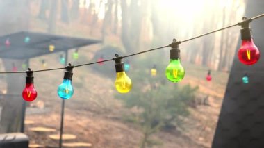 Renkli ampuller açık havada bir ipe tutunarak neşeli ve neşeli bir atmosfer yaratıyor.