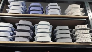 Bir mağazada katlanmış gömlekler. Bir erkek giyim mağazasında raflarda çeşitli renklerde katlanmış gömlekler ve desenler var.