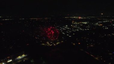 Gece Havai Fişek Gösterimi. Canlı bir havai fişek gösterisi, gece gökyüzünü aydınlatıyor. Kırmızı ve altın rengi havai fişeklerin parlak patlamaları ayrıntılı bir şekilde kaydediliyor..