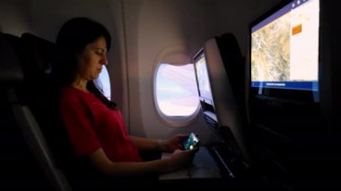 Uçak penceresinin yanında oturan yolculardan biri, In-Flight Entertainment 'ı kullanarak uçuş içi eğlence sistemini kullanmaktadır..