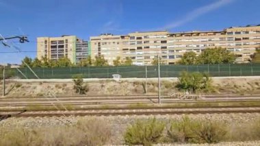 Madrid, İspanya 10.08.2024. Hareket halindeki bir trenden apartman ve demiryolu manzarası Madrid Guadalajara 'dan elektrik treni manzarası..