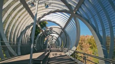 Madrid, İspanya 10.08.2024 Madrid parkındaki bir yaya köprüsü Madrid 'deki bir parkta karmaşık metalik yapıya sahip modern bir yaya köprüsü.