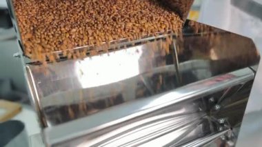 Bir makineden dökülen ve filtrelenen tahıl, ticari bir makine aracılığıyla dökülen ve filtrelenen tahılların yakından görüntüsü