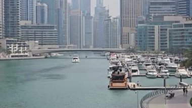 Dubai Marina 'daki yatlar ve yüksek binalar, Dubai Marina' nın manzaralı manzarası, rıhtım boyunca çok sayıda yatın yer aldığı arka planda gökdelenler var.