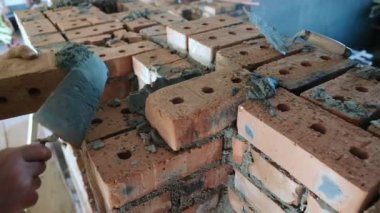 Tuğla ve Havan ile Masonluk Çalışması. Bir inşaat işçisinin tuğlalara harç uyguladığı tuğla döşeme sürecinin yakın plan görüntüsü