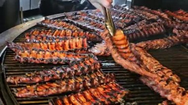 Şef ızgarada pirzola pişiriyor, şefin biri elinde maşayla ızgarada kaburga çeviriyor, et alevlerin üzerinde cızırdıyor..