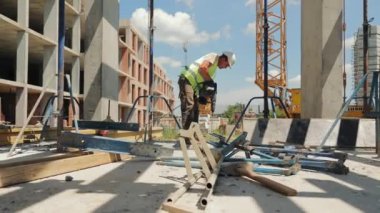 İnşaat işçisi inşaat alanında elektrikli alet kullanıyor. Bir inşaat işçisi açık hava inşaat alanında çalışırken elektrikli bir alet kullanır.