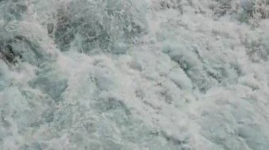 Çalkantılı Su Dalgaları 'nın yakın çekimi, türbülanslı su dalgalarının yakından görüntüsü, çarpışırken ve dönerken yoğun hareketi ve köpüren beyaz tepeleri gösteriyor..