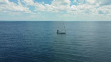 Sakin bir günde okyanusun ortasında yüzen yelkenli. Sakin bir günde engin bir okyanusta yüzen yalnız bir yelkenlinin huzurlu bir sahnesi.