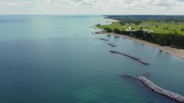 Bir sahil manzarası ve koruyucu dalgalı kıyı şeridi. Okyanusa uzanan koruyucu dalgaların yer aldığı kumlu bir sahil ve sahil manzarası.