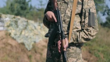 Saha operasyonları sırasında bir saldırı tüfeği tutan asker. Kamuflaj üniformalı, elinde makineli tüfek olan bir Ukraynalı asker sokakta dikiliyor.
