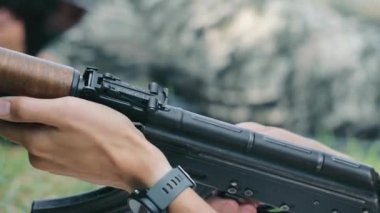 Asker, askeri eğitim sırasında bir saldırı tüfeği hazırlıyor. Askeri tatbikat sırasında bir saldırı tüfeğini ayarlayan ve hazırlayan Ukraynalı bir askerin yakın çekimi