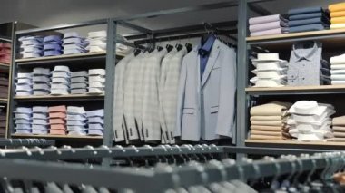 Perakende giyim mağazasında resmi gömlek ve takım elbiseler sergileniyor. Düzenli bir şekilde düzenlenmiş resmi gömlek ve takım elbise perakendecisi, farklı renklerde çeşitli katlanmış gömlek ve