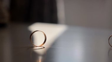 Yumuşak güneş ışığında alyansın yakın çekimi. Yumuşak güneş ışığıyla aydınlatılan basit bir nikah yüzüğünün yakın plan çekimi masanın üzerinde hassas bir gölge oluşturur.