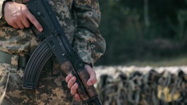 Kamuflajlı üniformalı bir saldırı tüfeği tutan asker. Kamuflajlı üniforma giymiş, elinde tüfekle bir askerin yakın çekimi..