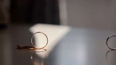 Sunlight 'taki nikah yüzüklerinin yakın çekimi. Düz bir yüzeyde, pencereden süzülen güneş ışığıyla güzelce aydınlatılan üç alyansın yakın plan çekimi.