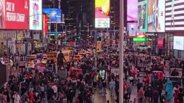 Times Meydanı 'ndaki gece sahnesinde ışıklı reklam panoları, Times Meydanı' nın gece görüşü aşağıdaki sokakları aydınlatan yüksek ve canlı reklam panolarını vurguluyor.,