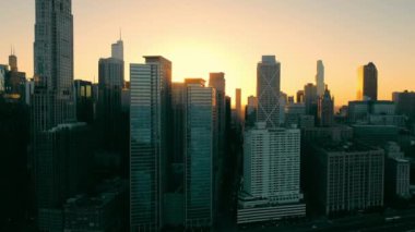 Şikago gökdelenleri dramatik gün batımı parıltılarıyla. Gün batımında Chicago ufuk çizgisi manzarası, gökdelenler arasında akan güneş ışığı ve şehir manzarası boyunca sıcak bir parıltı.