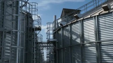 Metal Merdiven ve Platformları olan sanayi siloları. Metalik yapıları olan sanayi siloları, açık mavi gökyüzünün altında merdivenler ve platformlar da dahil.