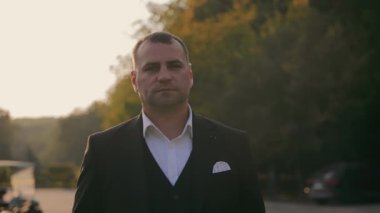 Bereketli yeşillik ve yumuşak akşam ışığı ile çevrili, huzurlu bir açık hava ortamında damat portresi, düşünceli ve klasik bir portre oluşturur.