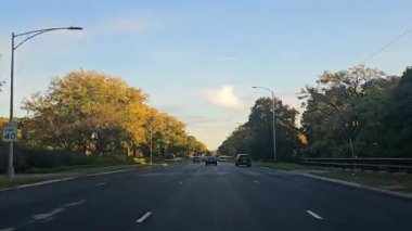 Gün batımında ağaçlarla çevrili Chicago Illinois Urban Yolu altın gün batımında parlayan ağaçlarla çevrili geniş şehir yolu..