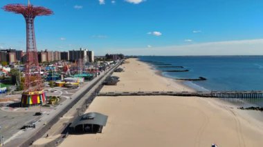 Coney Island Skyline ve Lunaparkı ile ikonik iskele, okyanus üzerinde uzanan ahşap bir iskelenin çarpıcı görüntüsü.