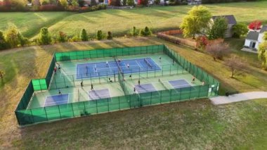 Pickleball Sahalarının Hava Görüntüsü, Pickleball sahalarının yeşil eskrim ve açık alanlarla çevrili oyuncularla oynanan dış top sahalarının drone çekimi