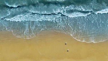 Okyanus Dalgaları ve Sandy Shore 'un yukarıdan görünüşü, yumuşak okyanus dalgalarının kumlu bir kumsalla buluşması, köpük ve el değmemiş altın kum desenleri.