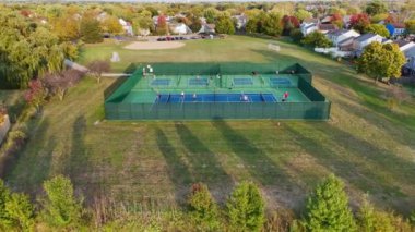 Sessiz bir mahalledeki yeşil tarlalar, ağaçlar ve banliyö evleriyle çevrili açık hava piknik sahaları manzarası