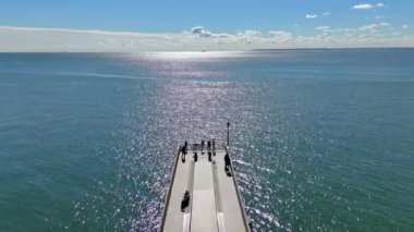 İskeleli parlak bir okyanusun havadan görünüşü, Coney Adası Sahili 'ndeki manzaranın tadını çıkaran insanlar..