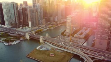 Chicago köprüsü ve güneş batarken gökyüzü ışıl ışıl parlıyor. Gün batımında Chicago Köprüsü 'nün ve şehir merkezindeki binaların havadan görünüşü, şehir mimarisi ve nehrin ışıklarıyla aydınlanıyor.