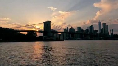Günbatımında Brooklyn Köprüsü 'nde Günbatımında New York şehrinin ufuk çizgisi, Doğu Nehri' ne yansıyan parlak altın ışınlar.