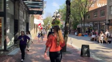 Canada Vancouver 24.09.2024 canlı bir şehir caddesinde geziniyor. Bir kadın, dükkanlar, insanlar ve açık hava dekorasyonlarıyla dolu canlı bir şehir sokağında yürüyor.