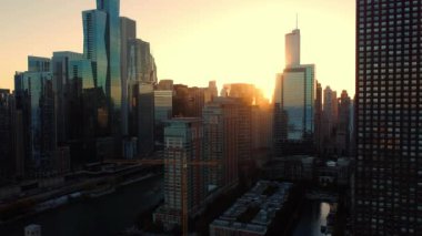 Gün batımında nehir yansımalarıyla Chicago gökdelenleri. Gün batımında Chicago gökdelenlerinin nefes kesici manzarası, cam cephelerindeki parıldayan yansımaları gösteriyor, Chicago Nehri.