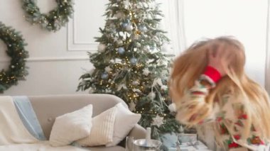 Güzel dekore edilmiş bir Noel ağacının yanında robot gibi dans eden mutlu kız. Neşeli çocuk Noel 'in tadını çıkarıyor.