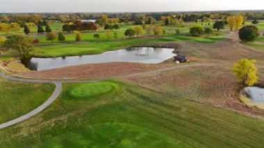 Gölet ve sonbahar yapraklı golf sahasının havadan görünüşü - dingin bir gölet, yemyeşil ve canlı sonbahar ağaçlarının yer aldığı bir golf sahasının manzarası