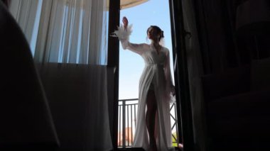 Saf cüppeli gelin uzanıyor, Saf cübbeli, tüylü kolları olan zarif gelin kapıda duruyor..