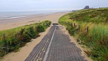 Kumsala giden Sandy Pathway Hollanda, Zandvoort, çimenli kum tepelerini kesen güçlendirilmiş bir yürüyüş yolu..