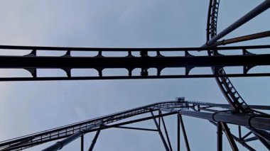 Aşağıdan bakıldığında lunapark trenlerinin, karanlık metal rayların ve hareket eden arabaların dramatik alçak açılı görüntüsü.