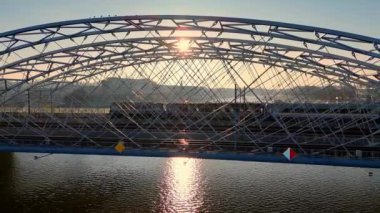 Günbatımında Krakow 'daki Vistula Nehri üzerindeki çelik kemer köprüsü, Polonya' nın Krakow kentindeki modern köprü, Vistula Nehri üzerindeki günbatımını yansıtıyor..