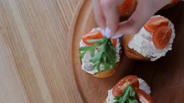 Domates soslu bruschetta 'ya roka eklemek, el bruschetta' nın üzerine taze roka koymak, domates ve krem peynirle.