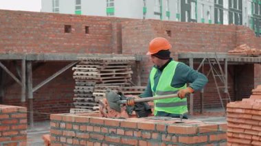 İnşaat işçileri inşaat alanında duvar örüyor, işçiler tuğla örüyor ve inşaat sahasına çimento saçıyor..