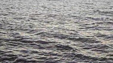 Gün batımında dalgalanan okyanus suyu yüzeyi, sakin okyanus dalgaları yumuşak günbatımı ışığını yansıtıyor..