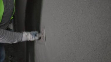 İç duvarda pürüzsüz alçı yapan işçilerin yakın çekimi işçilerin duvardaki alçıyı bir malayla düzleştirmesi..