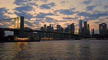 Brooklyn Köprüsü, gün batımında şehir siluetiyle, Brooklyn Köprüsü, günbatımında aydınlık New York şehrinin ufuk çizgisiyle.